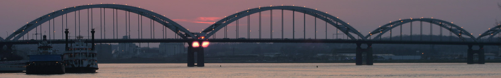 Centennial Bridge crossing the Mississippi River at sunset with the Celebration Belle riverboat